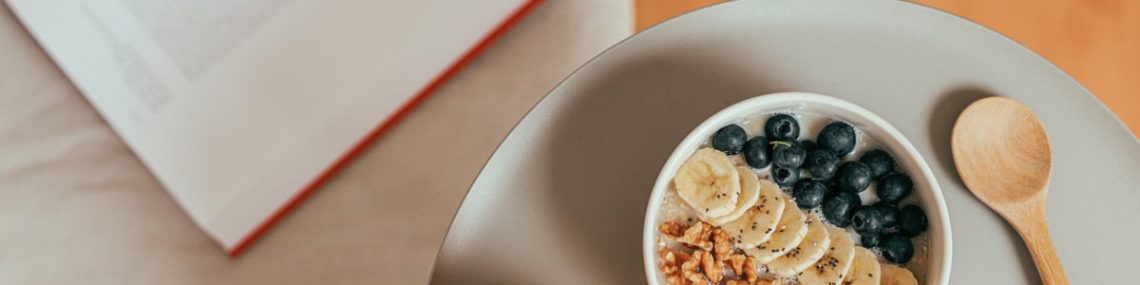 Top view of healthy breakfast with oatmeal, fresh fruit, and orange juice on a tray.